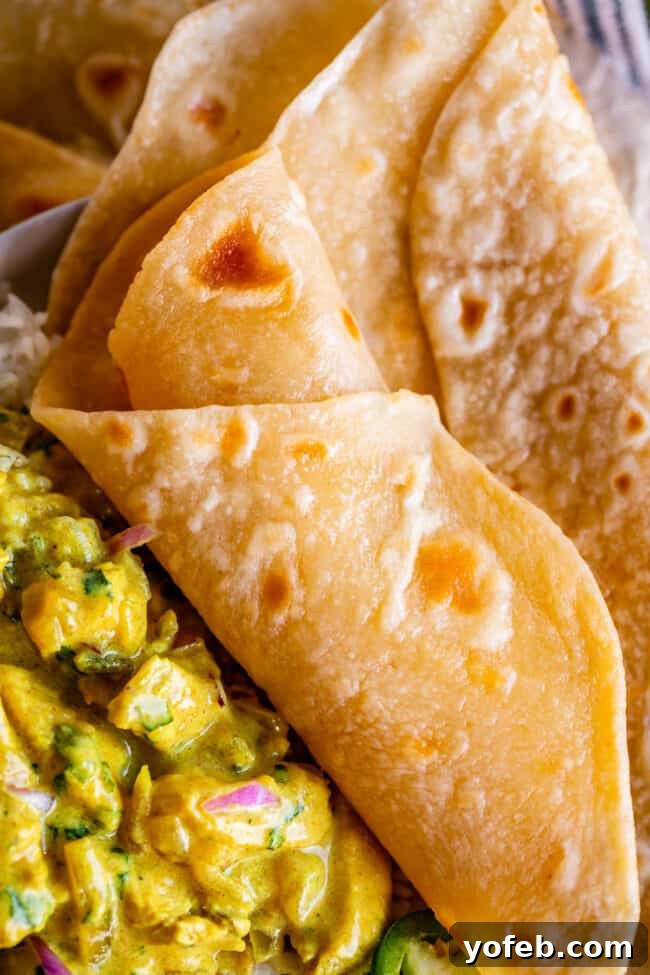 Roti Buttery Indian Flatbread Perfection 3 rolled indian flatbread on a plate with yellow curry.