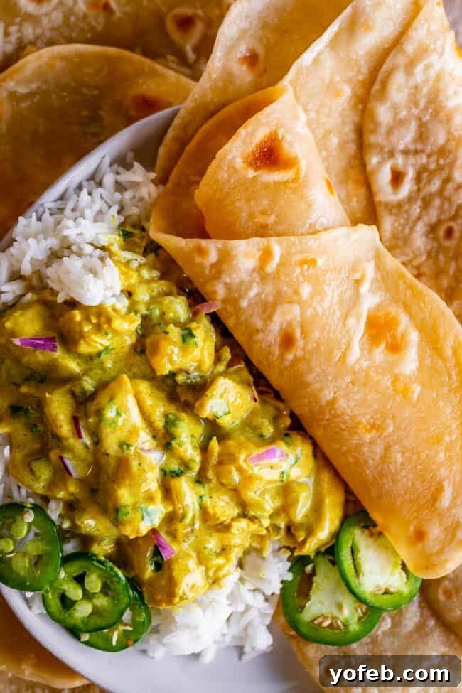 Roti Buttery Indian Flatbread Perfection 23 roti rolled up on a plate with curry and rice and jalapenos.