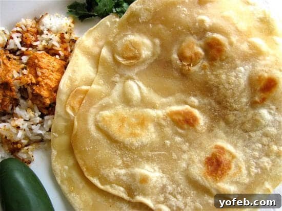 Roti Indian Flatbread from The Food Charlatan. I can't get enough of this Roti bread recipe! It's a super easy and delicious Indian flatbread. It is amazing when served with a saucy Indian dish and is perfect for sopping up extra sauce. Use lots of butter! #roti #Indian #butter #easy #flatbread #bread #howtomake old photo of roti with chicken tikka masala.