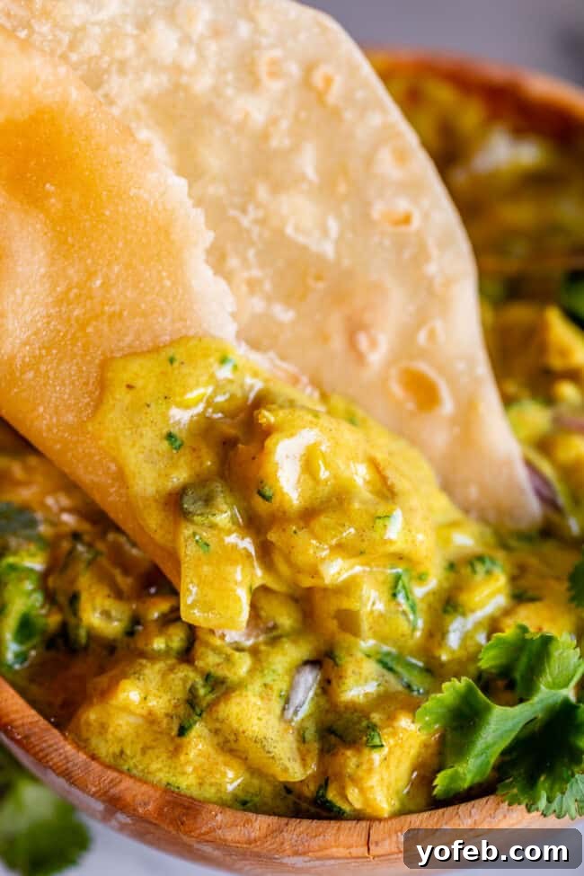 Roti Buttery Indian Flatbread Perfection 7 roti Indian bread dipped into yellow curry in wood bowl.