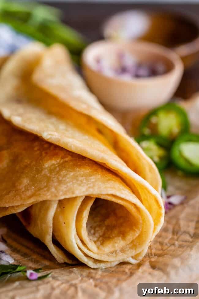 Roti Buttery Indian Flatbread Perfection 8 rolled up Indian flatbread on parchment paper with jalapeno and red onion.