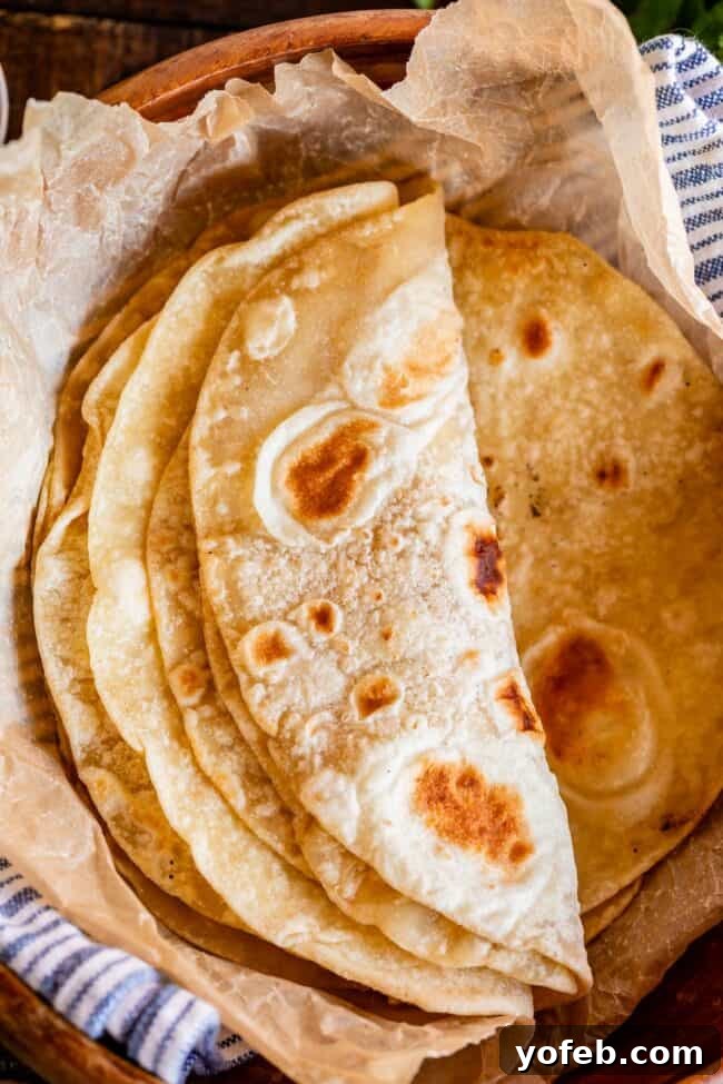 Roti Buttery Indian Flatbread Perfection 9 roti bread stacked in a wooden bowl with parchment paper.