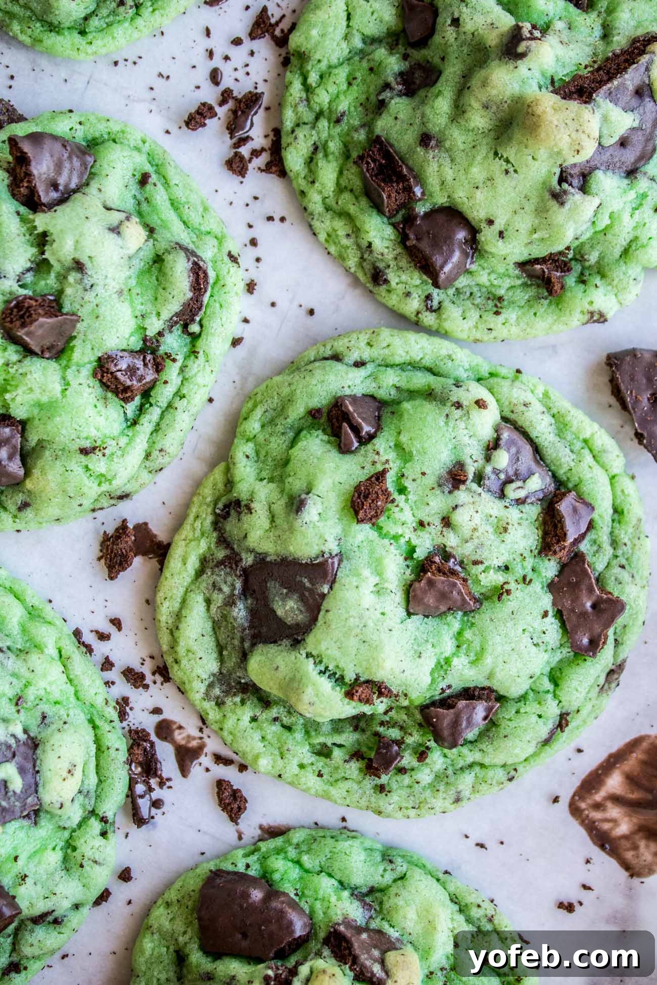 Thin Mint Mint Cookies: A double mint cookie dream with Girl Scout Thin Mints inside, perfect for St. Patrick's Day or any mint chocolate craving. #cookies #stpatricksday #thinmint #girlscout #green #mint Overhead shot of vibrant green Thin Mint Mint Cookies with crushed Thin Mints and chocolate chips scattered around them.
