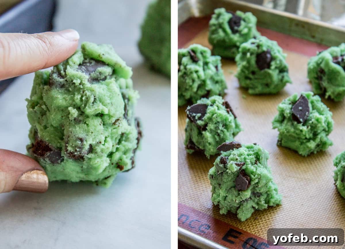 Thin Mint Mint Cookies: A double mint cookie dream with Girl Scout Thin Mints inside, perfect for St. Patrick's Day or any mint chocolate craving. #cookies #stpatricksday #thinmint #girlscout #green #mint Rows of perfectly formed, large green cookie dough balls, lightly flattened, arranged on a baking sheet lined with parchment paper.
