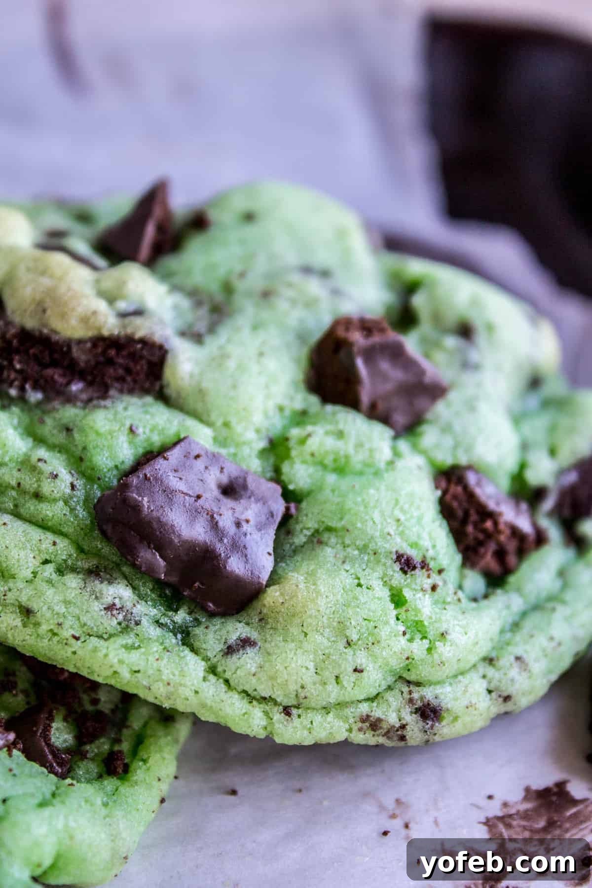 Thin Mint Mint Cookies: A double mint cookie dream with Girl Scout Thin Mints inside, perfect for St. Patrick's Day or any mint chocolate craving. #cookies #stpatricksday #thinmint #girlscout #green #mint A single, perfectly baked green Thin Mint Mint Cookie, studded with visible Thin Mint chunks, rests on a white background.
