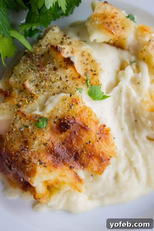 Effortless Make-Ahead Italian Mashed Potatoes for Holidays Golden crispy make-ahead mashed potatoes in a red casserole dish with a serving spoon.