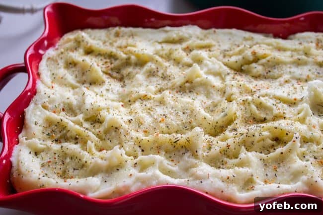 Casserole Dish of Make-Ahead Italian Mashed Potatoes Mashed potatoes smoothed into a casserole dish, topped with seasoning before baking.