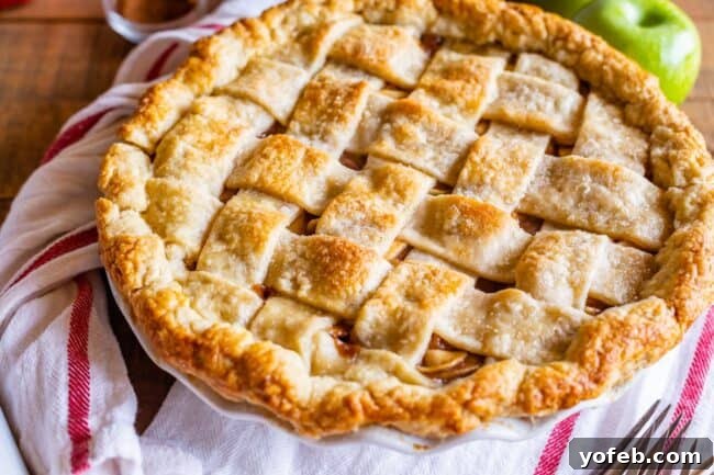 Grandma's Secret Apple Pie 16 A freshly baked homemade apple pie with a rustic lattice crust, resting on a white napkin, perfectly golden brown.