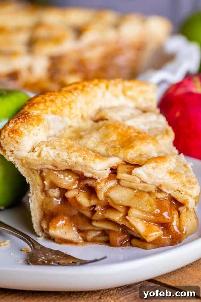 Grandma's Secret Apple Pie 17 A perfectly baked classic apple pie slice on a white plate with a silver fork, highlighting its inviting texture.