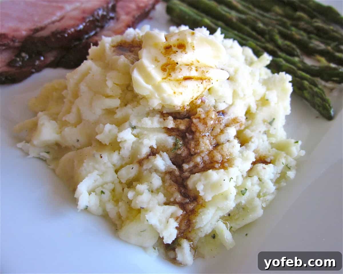 Fluffy Mashed Potatoes A close-up shot of fluffy, perfectly mashed potatoes in a white bowl, garnished with a sprinkle of chopped fresh chives for color and freshness.