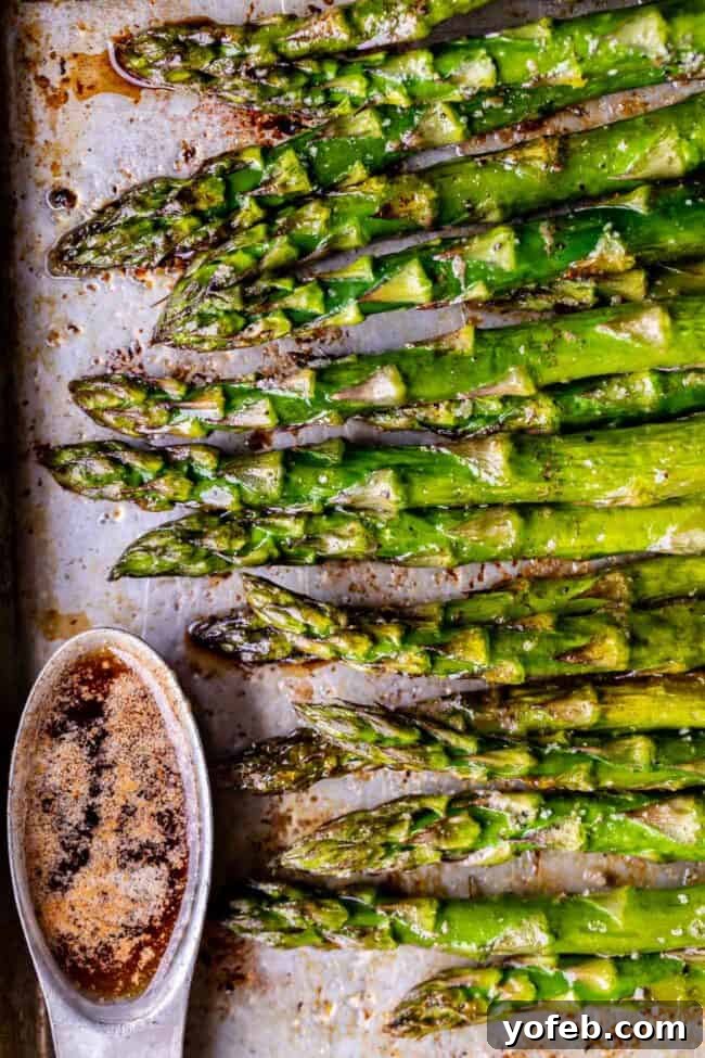 The secret to incredible asparagus: oven roasting and a drizzle of balsamic browned butter. A must-try recipe for vegetable lovers! #FoodPhotography #CookingTips #DeliciousFood A baking sheet filled with oven-roasted asparagus spears, alongside a small ramekin of golden-browned balsamic butter.