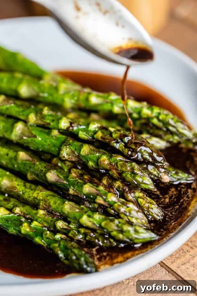 The perfect finishing touch: balsamic browned butter over tender roasted asparagus. A symphony of flavors in every bite! #VegetableSide #GourmetAtHome #CookingInspiration Roasted asparagus with luscious browned balsamic butter being artfully drizzled from a spoon.