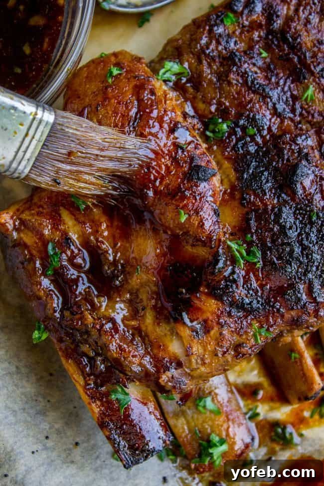 Glazing Slow Cooker Pork Ribs with Honey Balsamic Sauce A cook brushes a rich, dark glaze over a rack of slow cooker ribs on a baking sheet, preparing them for broiling.