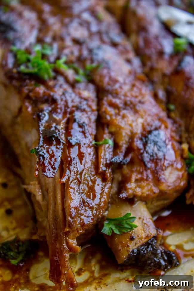 Garnished Honey Balsamic Slow Cooker Ribs A close-up of a plate of slow cooker spare ribs, garnished with fresh herbs, showcasing the glistening glaze and tender meat.