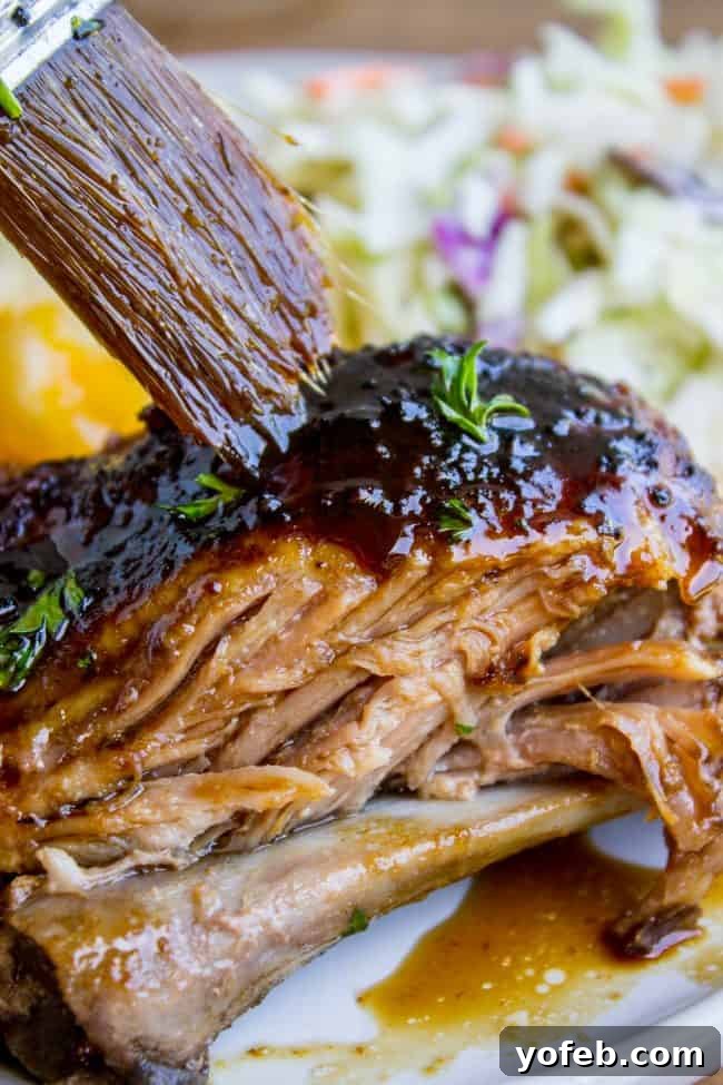 Applying Honey Balsamic Glaze to Slow Cooker Ribs A cook brushes a generous amount of honey balsamic glaze over slow cooker pork ribs on a baking sheet, preparing them for broiling.