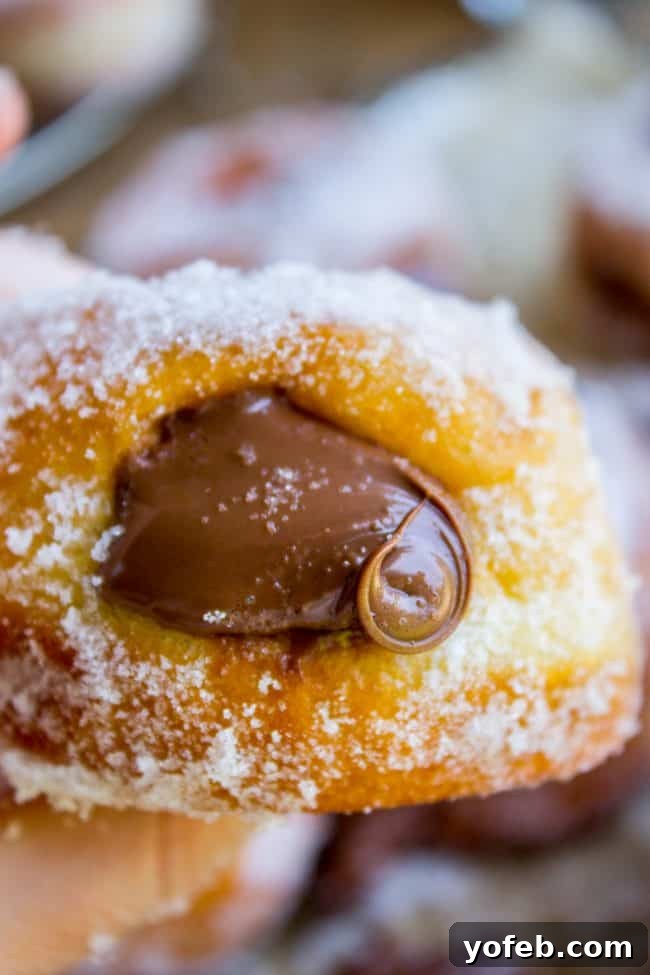 Indulgent Nutella-filled donuts with a beautiful swirl of hazelnut spread, showcasing the generous filling that makes these homemade treats irresistible. Plump Nutella-filled donuts artfully arranged, some showing a beautiful swirl of Nutella on top, highlighting their rich filling and sweet appeal.