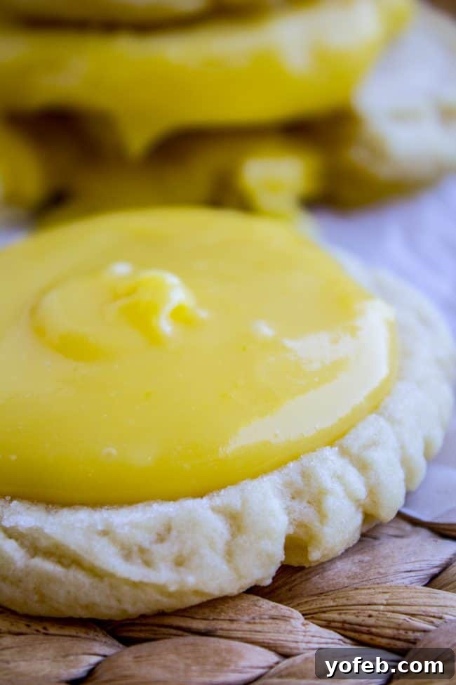Simple Lemon Curd Cookie Recipe - Perfect for Picnics and Parties Several lemon curd sugar cookie sandwiches arranged on a wooden board, with a focus on their inviting golden-brown texture.
