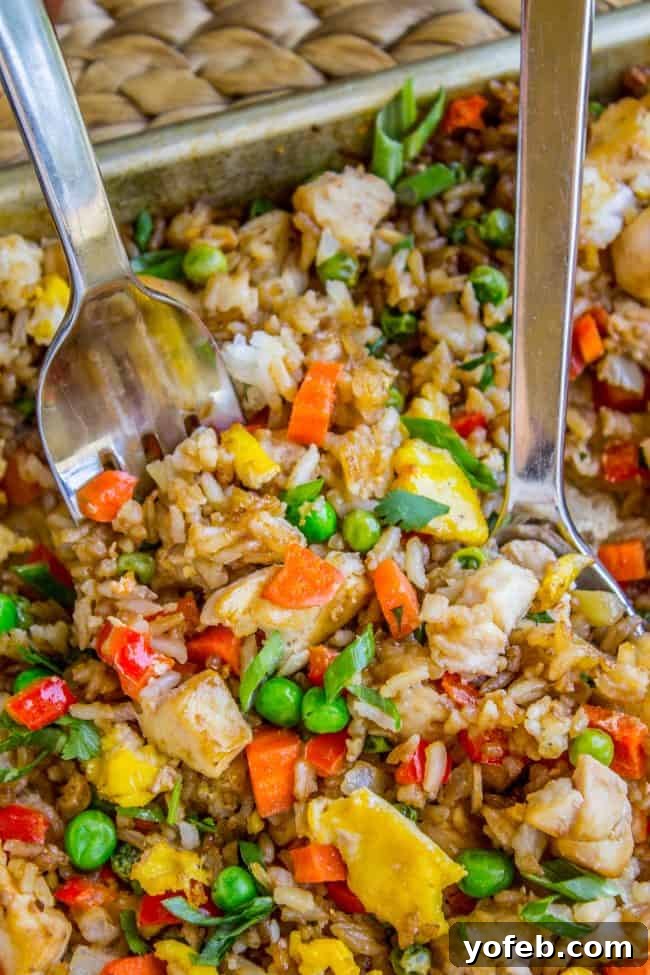 A large serving of Sheet Pan Chicken Fried Rice, vibrant with colors from vegetables and garnished with fresh green onions