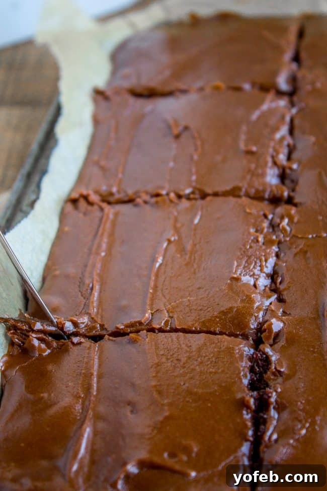 How to Easily Cut and Serve Your Delicious Texas Chocolate Sheet Cake for Any Occasion. A butter knife expertly cutting large, square slices of Texas Chocolate Sheet Cake, showcasing its perfect texture.