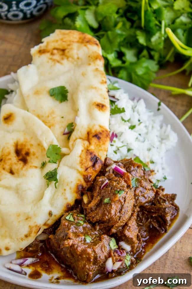 Slow Cooker Beef Curry: A complete meal with rice and naan. A vibrant platter of Slow Cooker Beef Curry, generously topped with fresh cilantro, accompanied by fluffy white rice and warm, soft naan bread. This inviting dish promises rich flavors and tender beef.