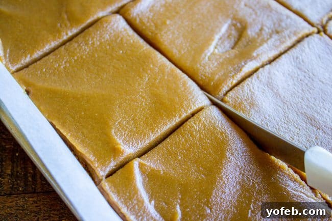 Slicing Homemade Caramel Cake A knife expertly cutting a perfectly frosted caramel cake into neat squares, emphasizing the cake's soft texture and thick icing.