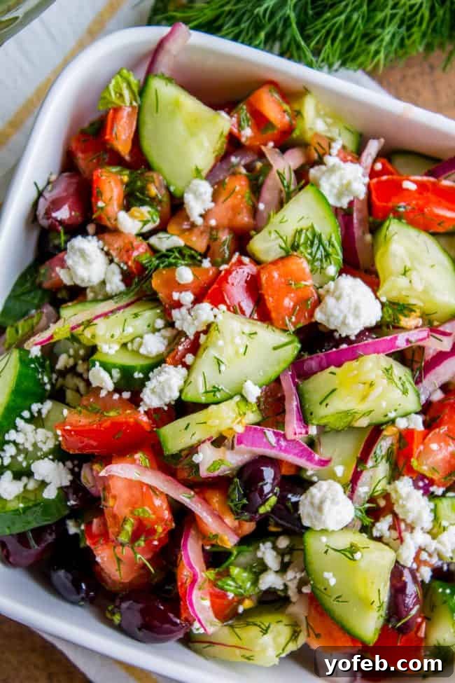 Easy Greek Salad Recipe with Feta: Fresh ingredients, simple vinaigrette, and abundant crumbled feta make this the best side dish for any occasion. #cucumber #tomato #salad #olive #kalamata #mint #dill #fresh #recipe #dressing #healthy #easy #authentic #feta #oregano #traditional #chopped #classic A crisp, healthy Greek Tomato Cucumber Salad with Feta Cheese, served in a white bowl, featuring chopped tomatoes, cucumbers, red onions, and Kalamata olives.