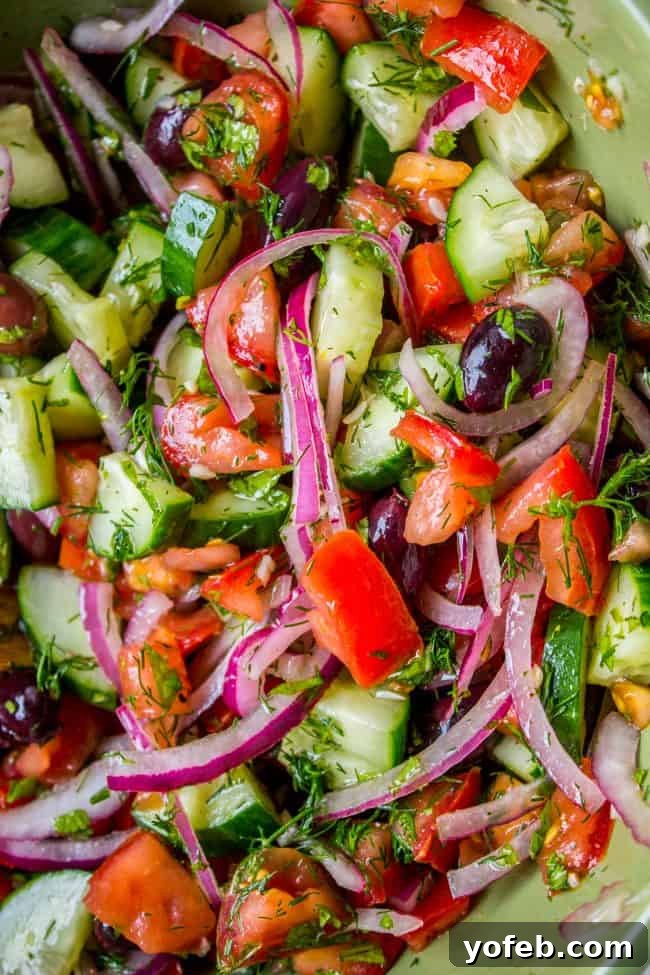 Assembled Greek Salad with Feta: Fresh cucumbers, tomatoes, red onions, Kalamata olives, and feta, awaiting the simple homemade vinaigrette. #greeksalad #feta #freshsalad #mediterraneanfood #healthychoices A beautifully assembled Greek Tomato Cucumber Salad, generously topped with crumbled feta cheese, red onion, and Kalamata olives, ready to be dressed.