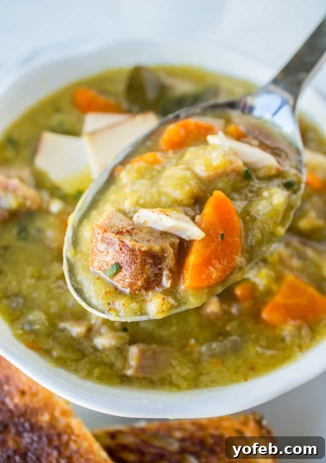 Hearty Split Pea and Ham Soup 3 A spoon meticulously lifting a rich, thick bite of split pea soup from a rustic ceramic bowl, showcasing the perfect texture.