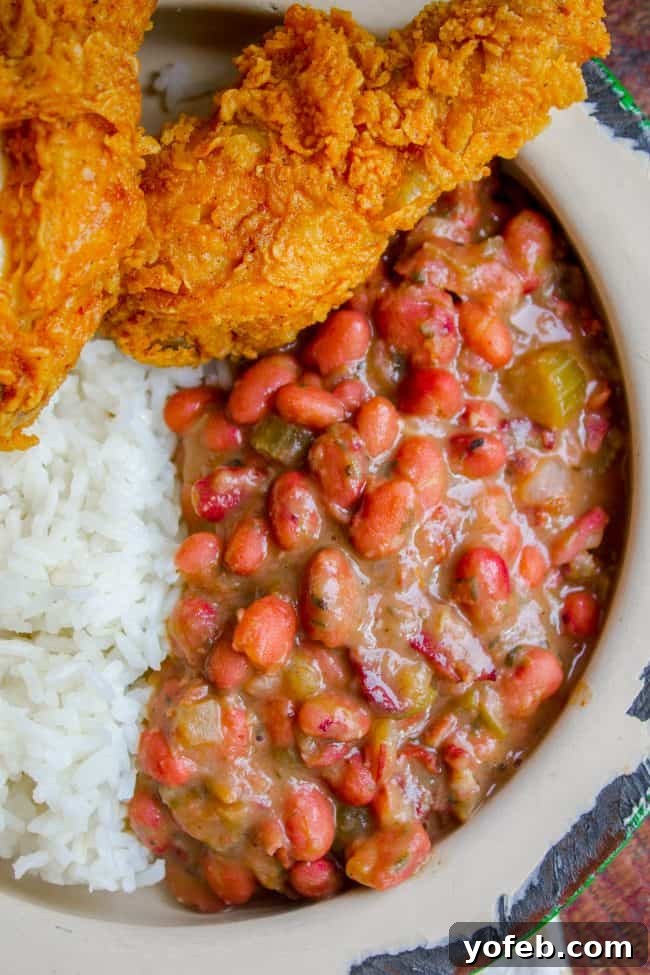 Soulful Cajun Red Beans and Rice 2 A hearty plate of creamy red beans and rice, perfectly garnished, served alongside crispy fried chicken.