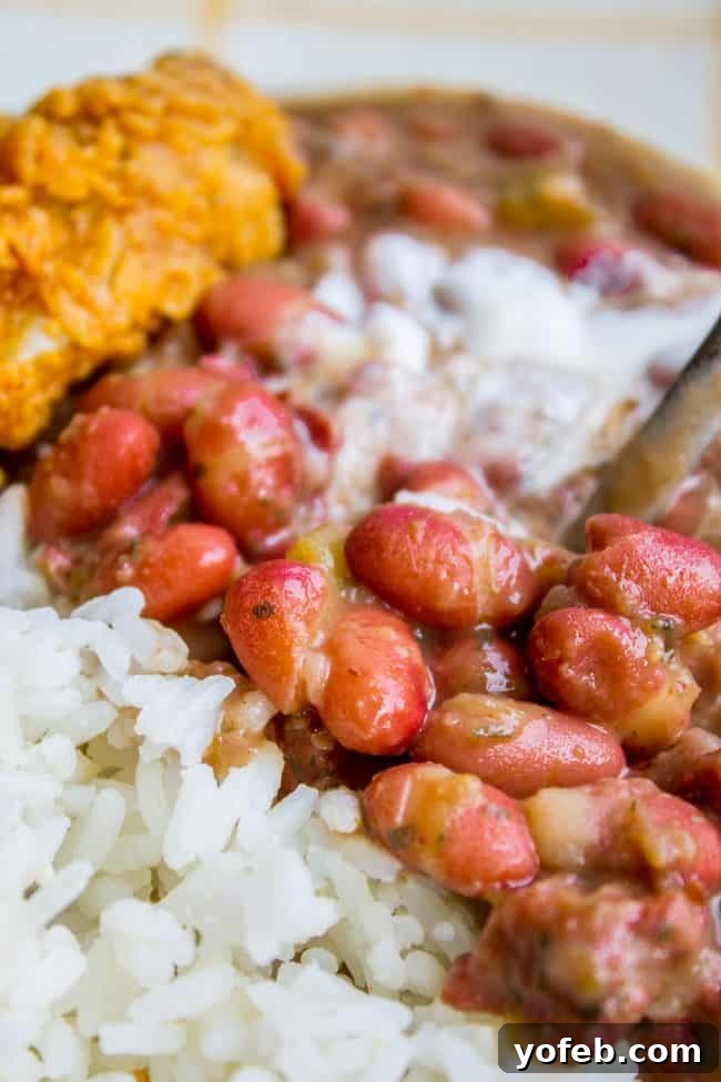 Soulful Cajun Red Beans and Rice 9 A close-up shot of a serving of red beans and rice, highlighting the creamy texture and rich color, with fried chicken in the background.