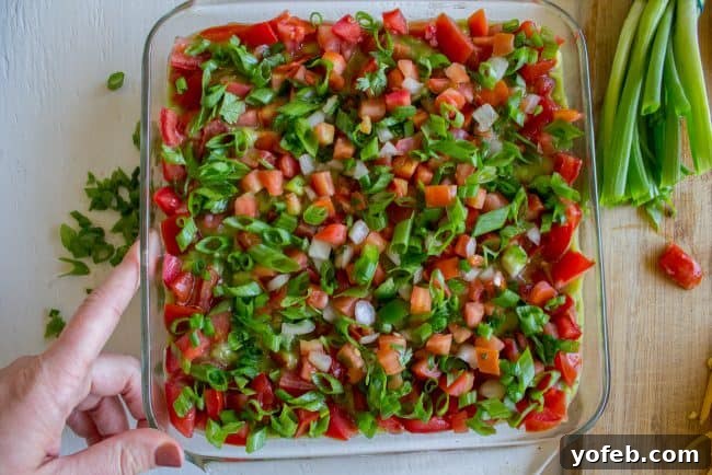 Carols Epic Seven Layer Bean Dip 10 onions and tomatoes layered on top of bean dip.