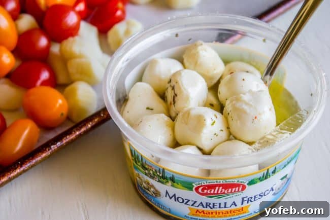 A close-up of tender gnocchi and juicy cherry tomatoes roasted to perfection on a sheet pan, awaiting mozzarella.