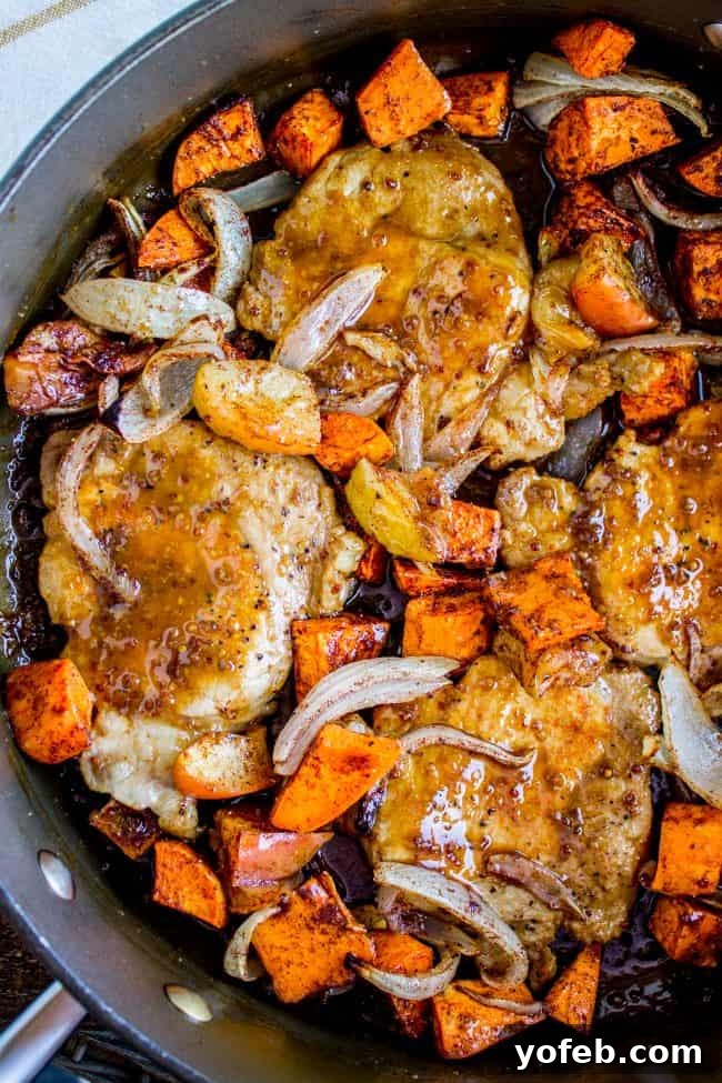 Glazed Pork Chops with Apples from The Food Charlatan. These Pork Chops with Apples are such an easy weeknight dinner! They are done in just a few minutes, and finished off in a delicious apple cider glaze. The cinnamon-spiced roasted apples and sweet potatoes will have your house smelling like autumn in no time. #apple #roasted #fall #cinnamon #applecider #onion #dinner #easy #weeknight #easy #fried #recipe #boneless #sauce #healthy #glazed Pan-seared pork chops, sweet potatoes, apples, and onions nestled in a cast iron skillet, with a rich glaze.