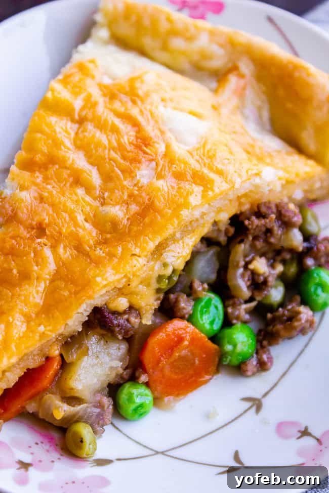 One Skillet Shepherd's Pot Pie from The Food Charlatan. It's like Shepherd's Pie and Chicken Pot Pie got together and had a baby to make a One Skillet Shepherd's Pot Pie! Regular skillet shepherd's pie would feature mashed potatoes, but instead we are covering ours up with a super flaky pie crust, just like it's a pot pie. It's comfort food heaven!! #recipe #easy #best #beef #traditional #skillet #castiron #casserole #withgravy #withcrust #cheddar #onepot #cheese #carrots #peas #flaky #crust skillet shepherds pie closeup