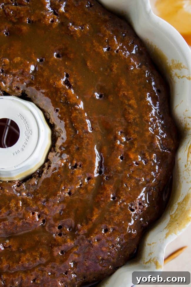 Ginger Sticky Toffee Pudding Cake from The Food Charlatan. This is a classic English dessert! The chopped dates make it incredibly moist as is, but then we go and dump buttery caramel sauce all over the top of it while it's warm. It's ridiculous and you will love it! #cake #pudding #english #englishpudding #toffee #sticky #ginger #recipe #easy #baked #dates #traditional #holidays #thanksgiving #Christmas #fall #fallbaking #spice #spicecake #caramel #caramelsauce Close-up of a slice of Ginger Sticky Toffee Pudding Cake with sauce