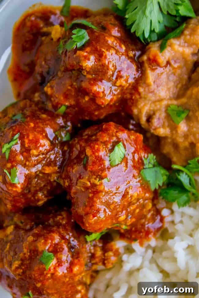 Simmering Mexican Meatballs in Enchilada Sauce A large pot of Mexican meatballs simmering in a rich red enchilada sauce.