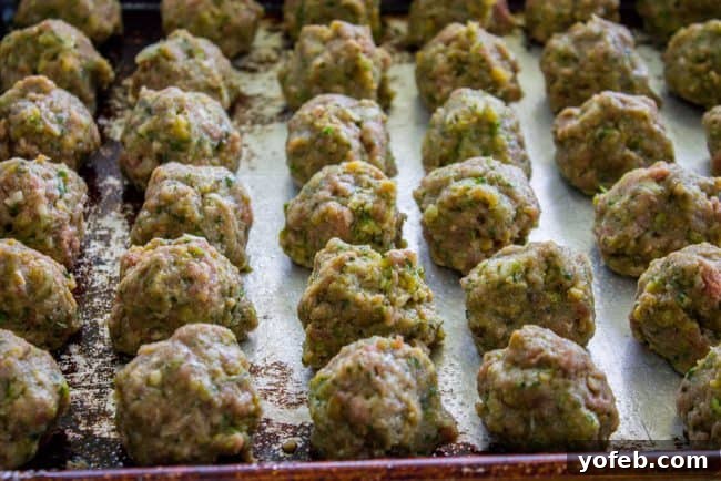 Ready to Bake: Perfectly Shaped Meatballs Rolled meatballs arranged on a baking sheet before baking.