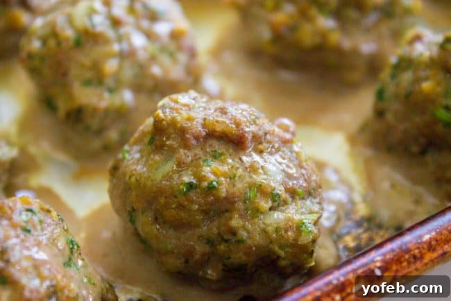 Baked Meatballs Ready for the Enchilada Sauce Simmer Freshly baked Mexican meatballs being transferred to a simmering enchilada sauce.