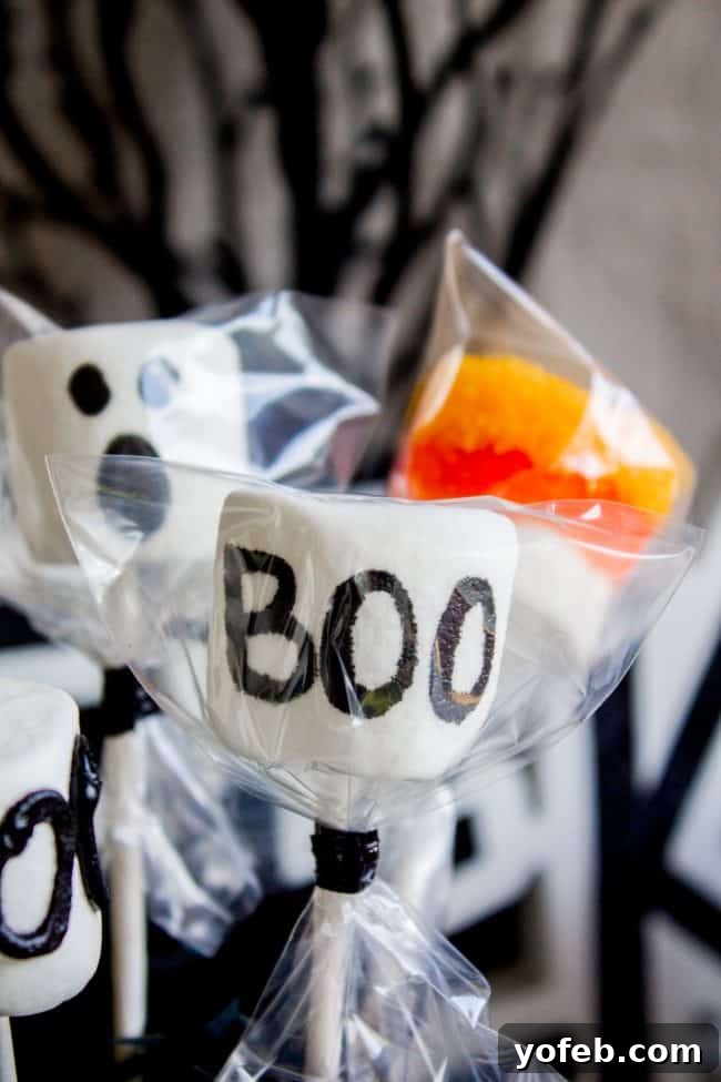 Halloween Marshmallow Pop as a Party Favor: Individually wrapped treat. An individually wrapped Frankenstein marshmallow pop, enclosed in a clear cellophane bag and secured with a festive orange ribbon, signifying its readiness as a Halloween party favor.