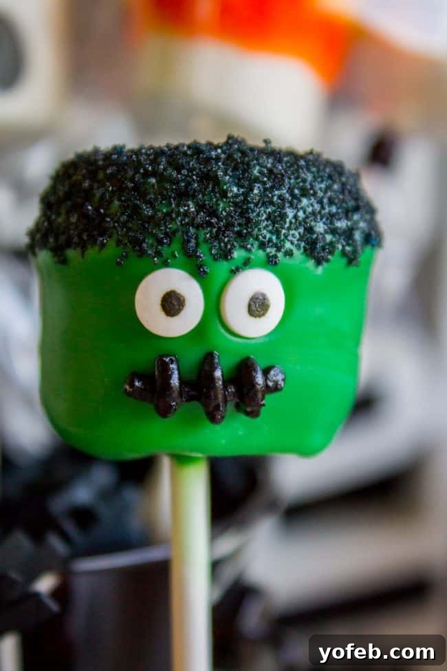 Frankenstein Marshmallow Pop: A fun and simple Halloween treat tutorial. A close-up shot of a Frankenstein marshmallow pop, showcasing its vibrant green candy coating, jagged black sanding sugar 'hair', and bright candy eyes, all on a lollipop stick.