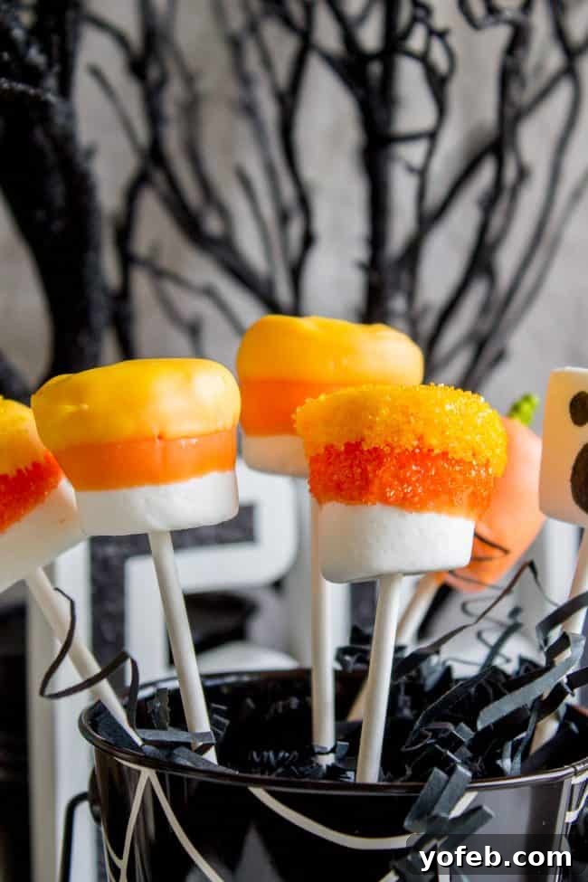 Completed Halloween Marshmallow Pops arranged for display: A festive centerpiece. A creative display of completed Halloween marshmallow pops standing upright in a decorative bucket, showcasing various monster, ghost, and mummy designs ready for a party.