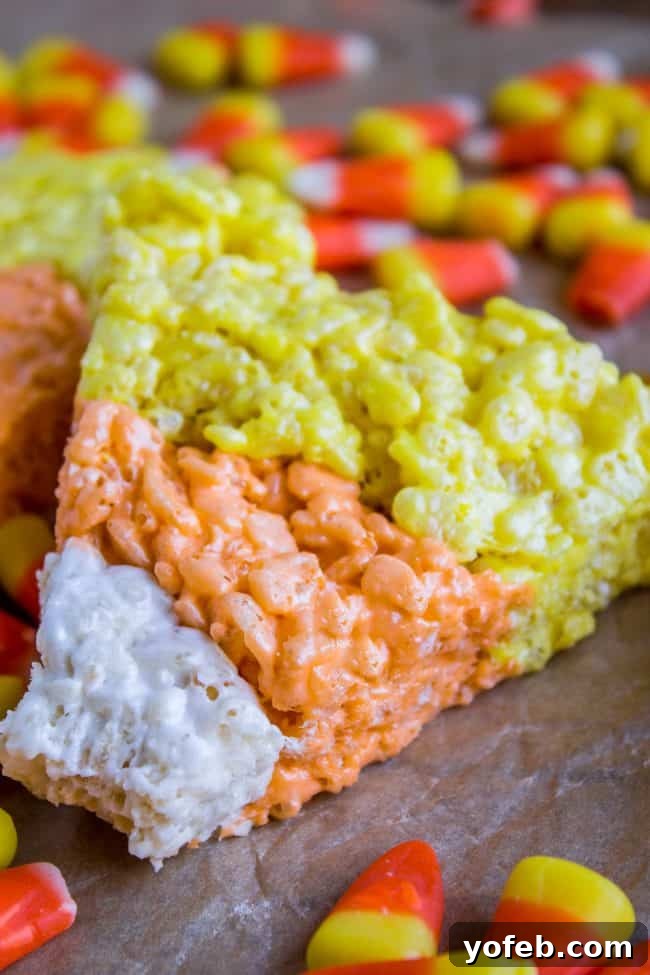 Holding a Chewy Halloween Rice Krispie Treat A hand holding a piece of Candy Corn Rice Krispie Treat, with the chewy texture clearly visible.