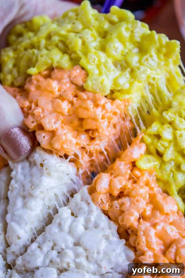 The Perfect Gooey Candy Corn Rice Krispie Treat A single piece of Candy Corn Rice Krispie Treat, cut into a triangle, showing its sticky texture.