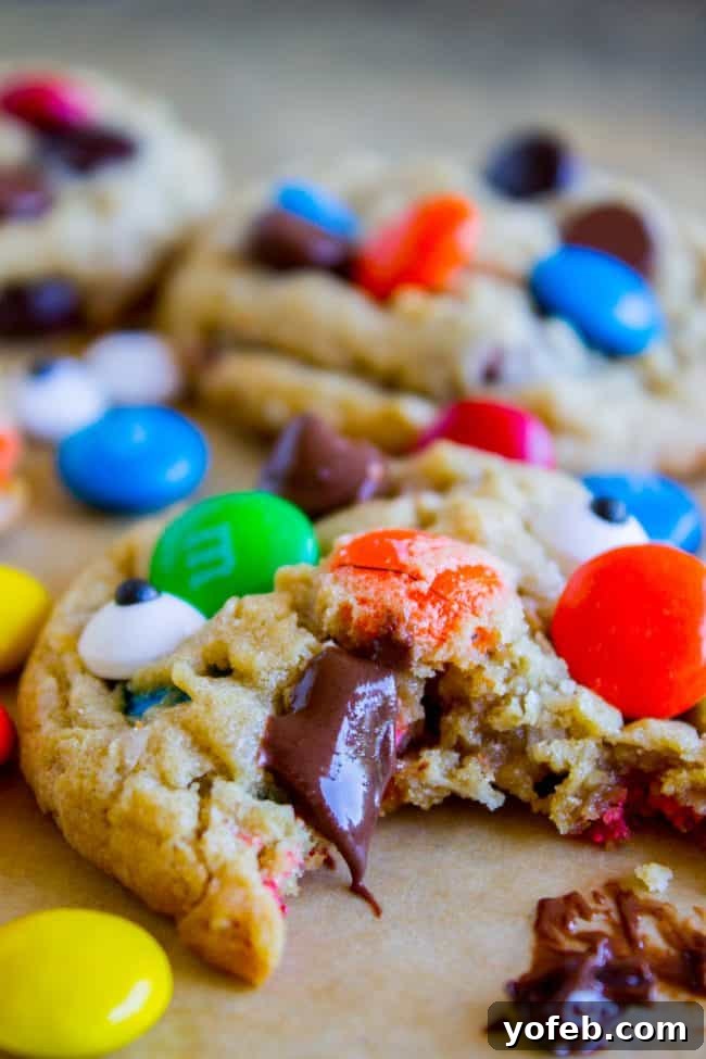 Monster Cookie close-up with a bite. A monster cookie with a bite taken out, revealing its soft, chewy interior with melted M&Ms.
