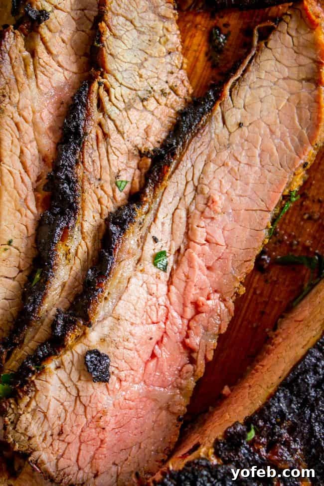 How to Cook Tri Tip (Grilled or Oven-Roasted) from The Food Charlatan. If you've never had tri tip, you haven't lived! I will show you how to cook tri tip on the grill or in the oven. It's SO easy and the flavor is unbeatable! We always had tri tip for Christmas dinner growing up, it's an impressive holiday dinner! A garlic marinade rub and tri tip roast recipe for a Christmas meal or summer bbq? Yes, please! All the tender, juicy, beefy goodness of steak but at a much more affordable price. Long, thin slices of medium-rare tri-tip steak arranged on a platter, showcasing the beautiful internal color and juicy texture.