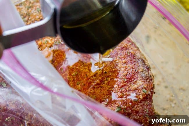 How to Cook Tri Tip (Grilled or Oven-Roasted) from The Food Charlatan. If you've never had tri tip, you haven't lived! I will show you how to cook tri tip on the grill or in the oven. It's SO easy and the flavor is unbeatable! We always had tri tip for Christmas dinner growing up, it's an impressive holiday dinner! #intheoven #grilled #garlic #recipes #marinade #dinner #bbq #howtocook #rub #sandwich #santamaria #seasoning #steak #baked #roast #Christmas #Thanksgiving #Easter #beef #best Raw tri-tip steak liberally seasoned with a savory herb and garlic marinade, ready for cooking.