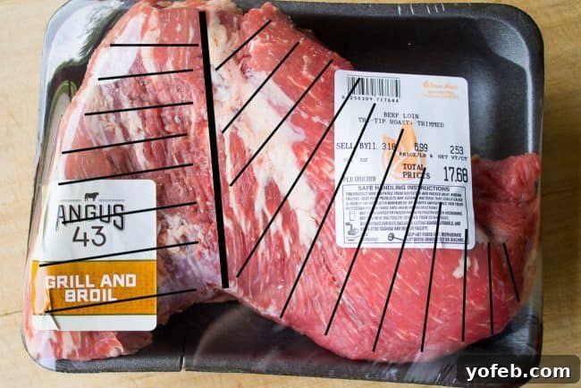How to Cook Tri Tip (Grilled or Oven-Roasted) from The Food Charlatan. If you've never had tri tip, you haven't lived! I will show you how to cook tri tip on the grill or in the oven. It's SO easy and the flavor is unbeatable! We always had tri tip for Christmas dinner growing up, it's an impressive holiday dinner! #intheoven #grilled #garlic #recipes #marinade #dinner #bbq #howtocook #rub #sandwich #santamaria #seasoning #steak #baked #roast #Christmas #Thanksgiving #Easter #beef #best Raw tri-tip roast with black lines illustrating the two different grain directions for proper slicing.