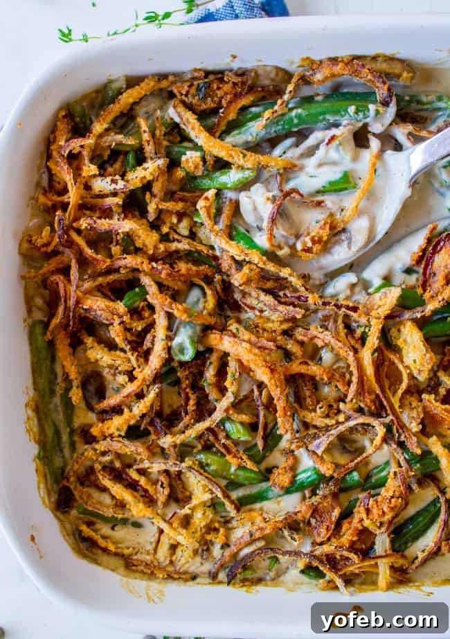 Perfect Green Bean Casserole for Your Holiday Feast Green Bean Casserole from scratch with homemade crispy fried onions and a serving spoon.