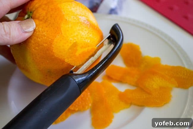 Orange Zest Preparation Carefully peeling a fresh orange, preparing the zest for vibrant cranberry sauce.