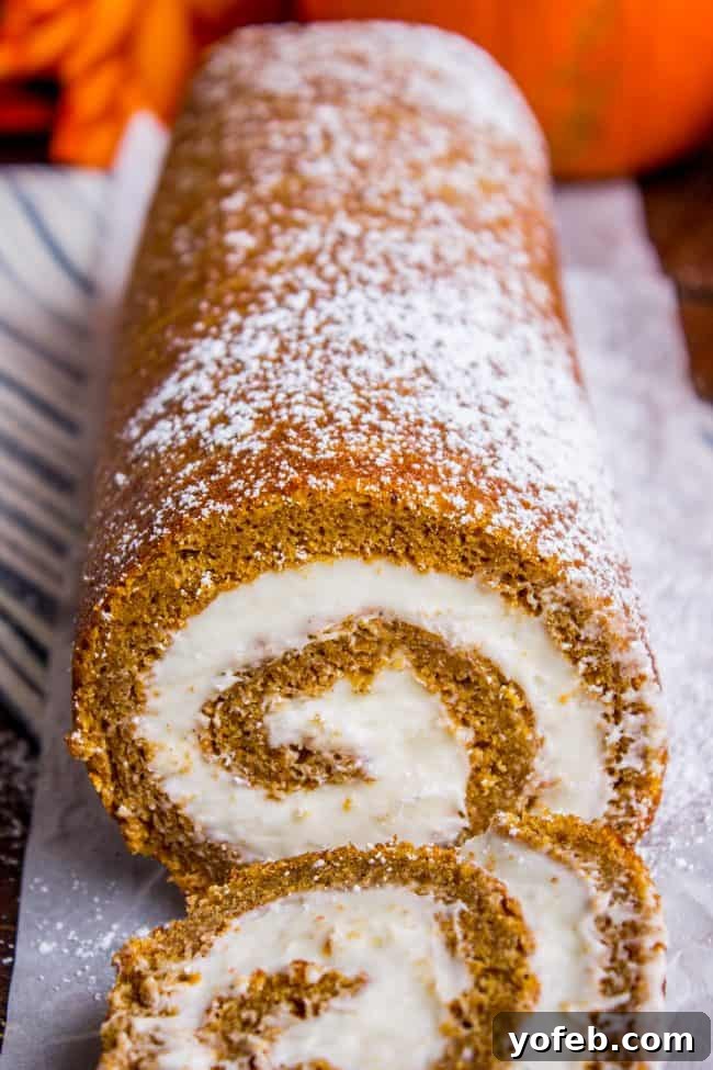 Pumpkin roll with cream cheese frosting, lightly dusted with powdered sugar, showcasing a perfect swirl.